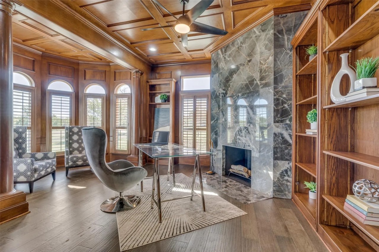 Custom home office restyle with wood paneling, coffered ceiling, marble fireplace, and built-in shelving