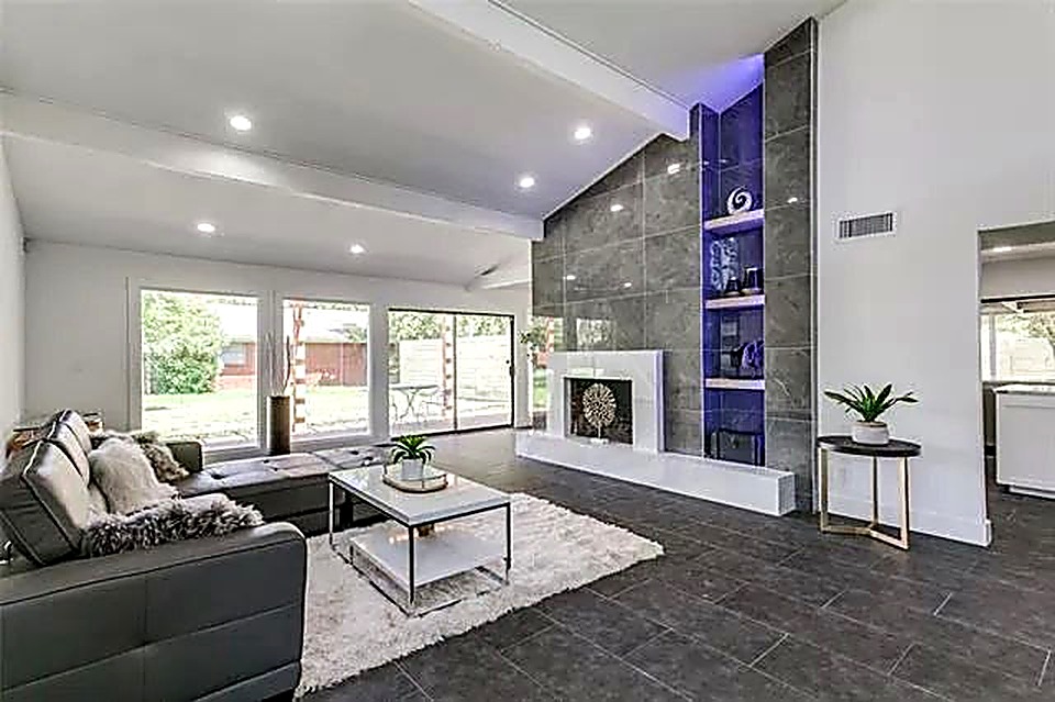 Vaulted ceiling living room with custom tile fireplace and backlit display niche