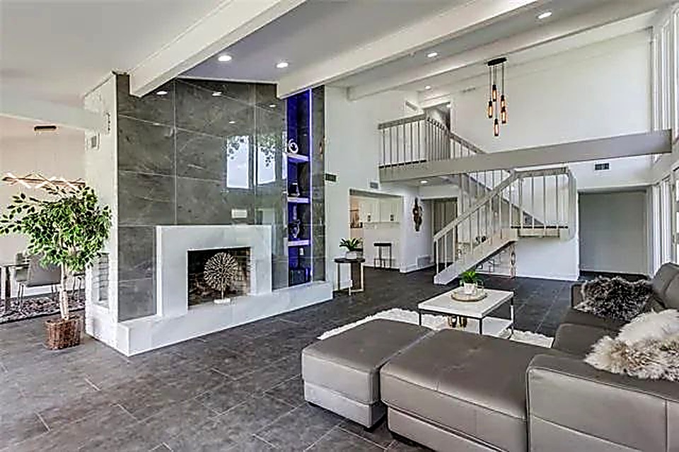 Open-concept living room restyle with vaulted ceiling, staircase, and dark tile flooring